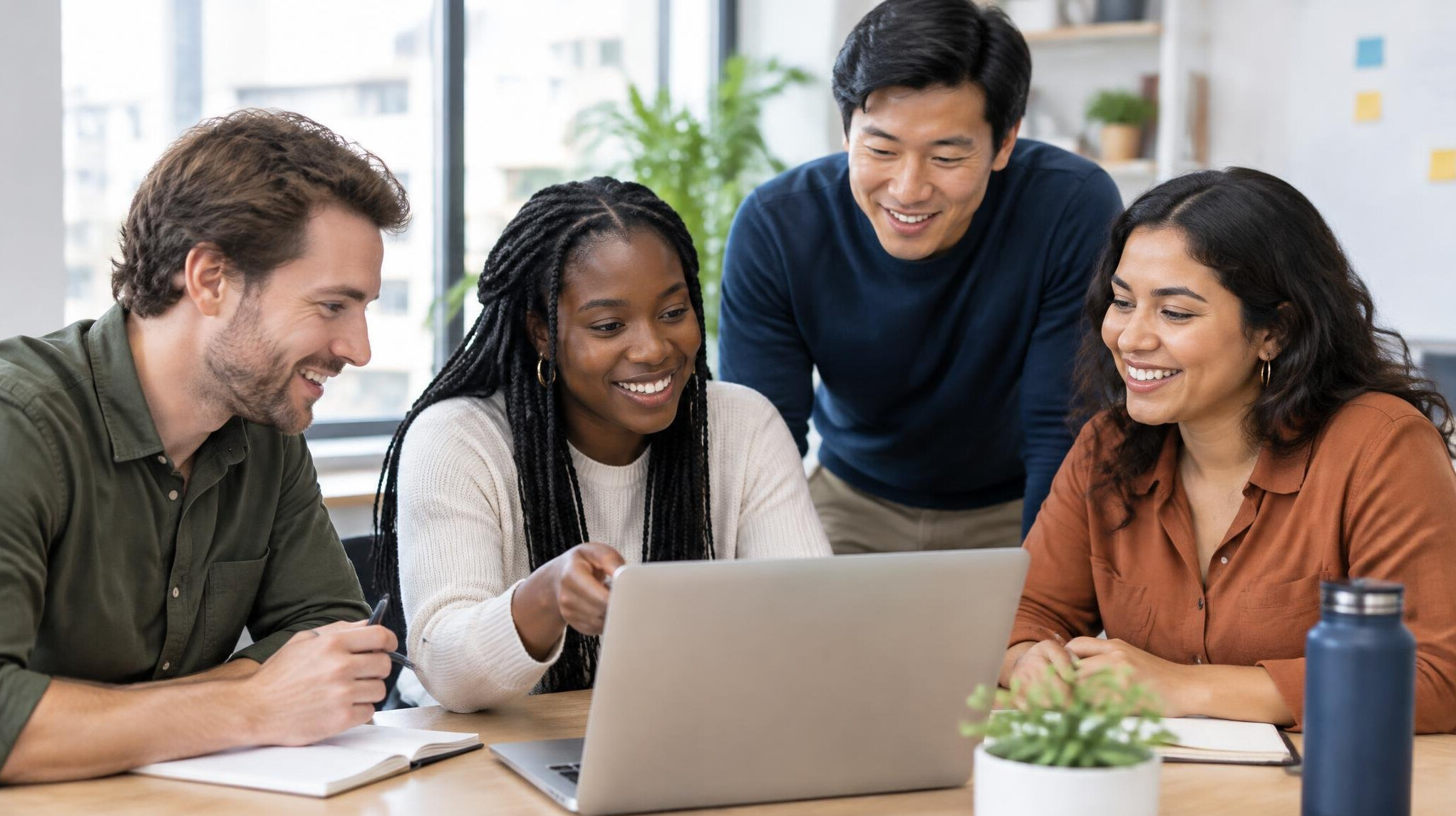 Team of colleagues collaborating around a laptop